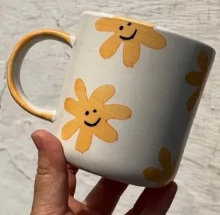 Caneca pintada à mão com flores amarelas sorridentes